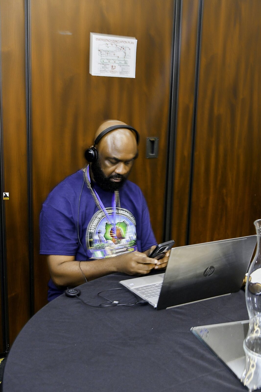 Man in a convention T-shirt seated at a laptop
