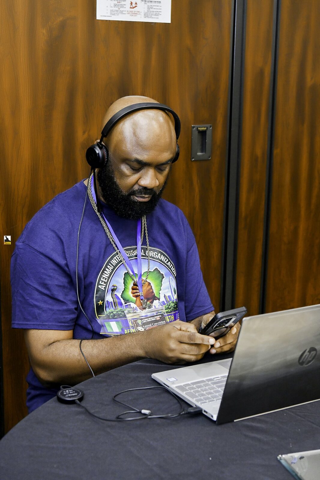 Man in a convention T-shirt seated at a laptop