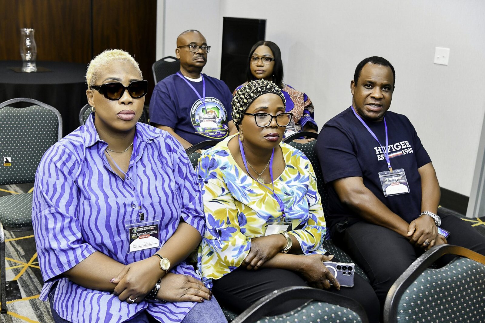 Attendees in blue and yellow clothing seated in rows