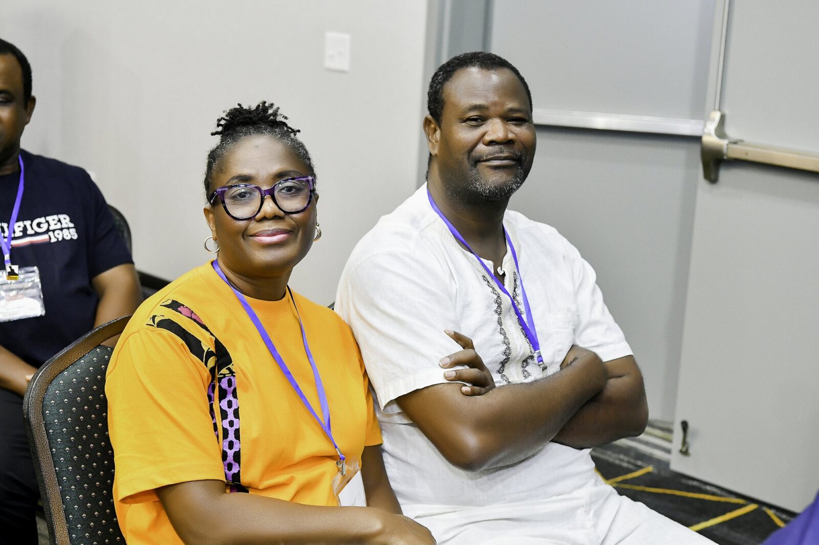 Woman in a mustard top seated beside a man in white