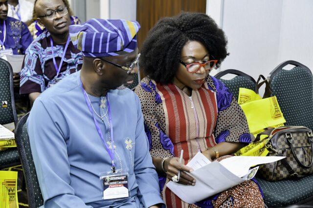 A man in a striped cap and a woman in orange looking at papers