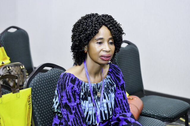 Woman in blue patterned clothing seated in the room