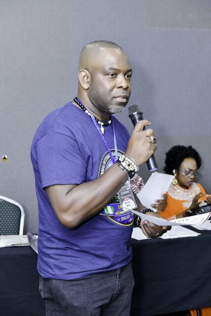 Man in a convention T-shirt holding a microphone