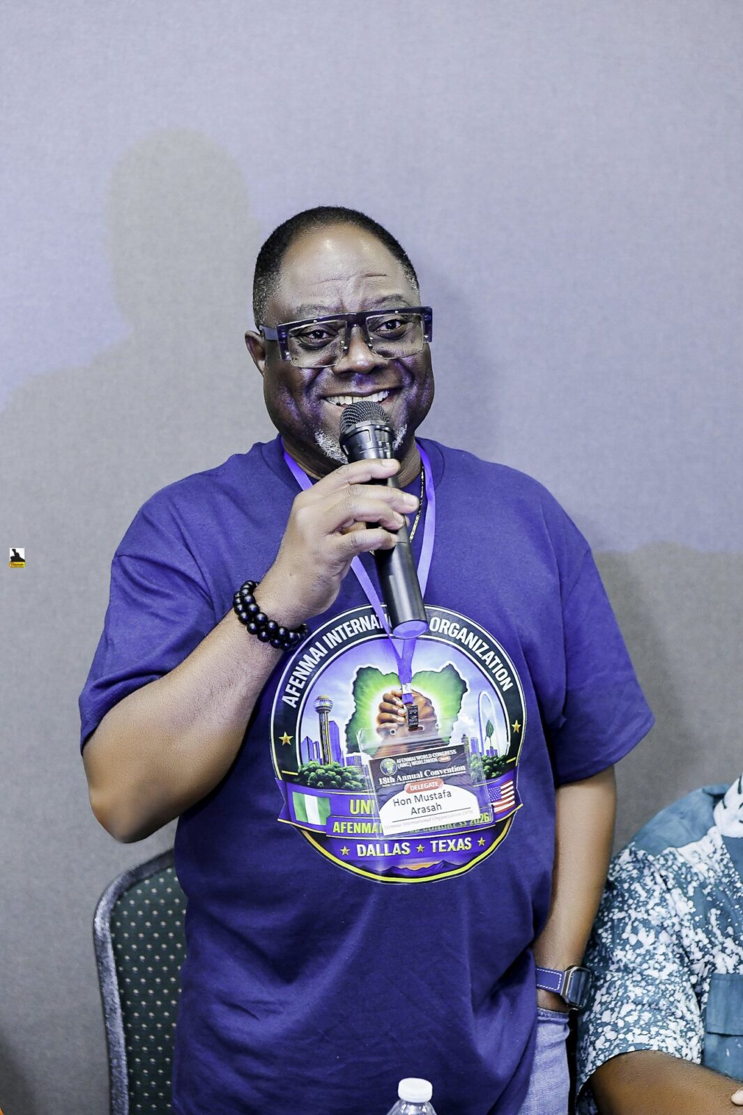 Man in a convention T-shirt speaking into a microphone