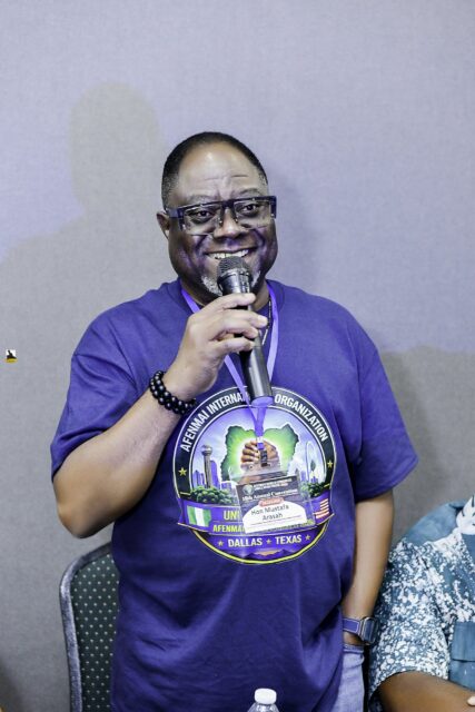 Man in a convention T-shirt speaking into a microphone