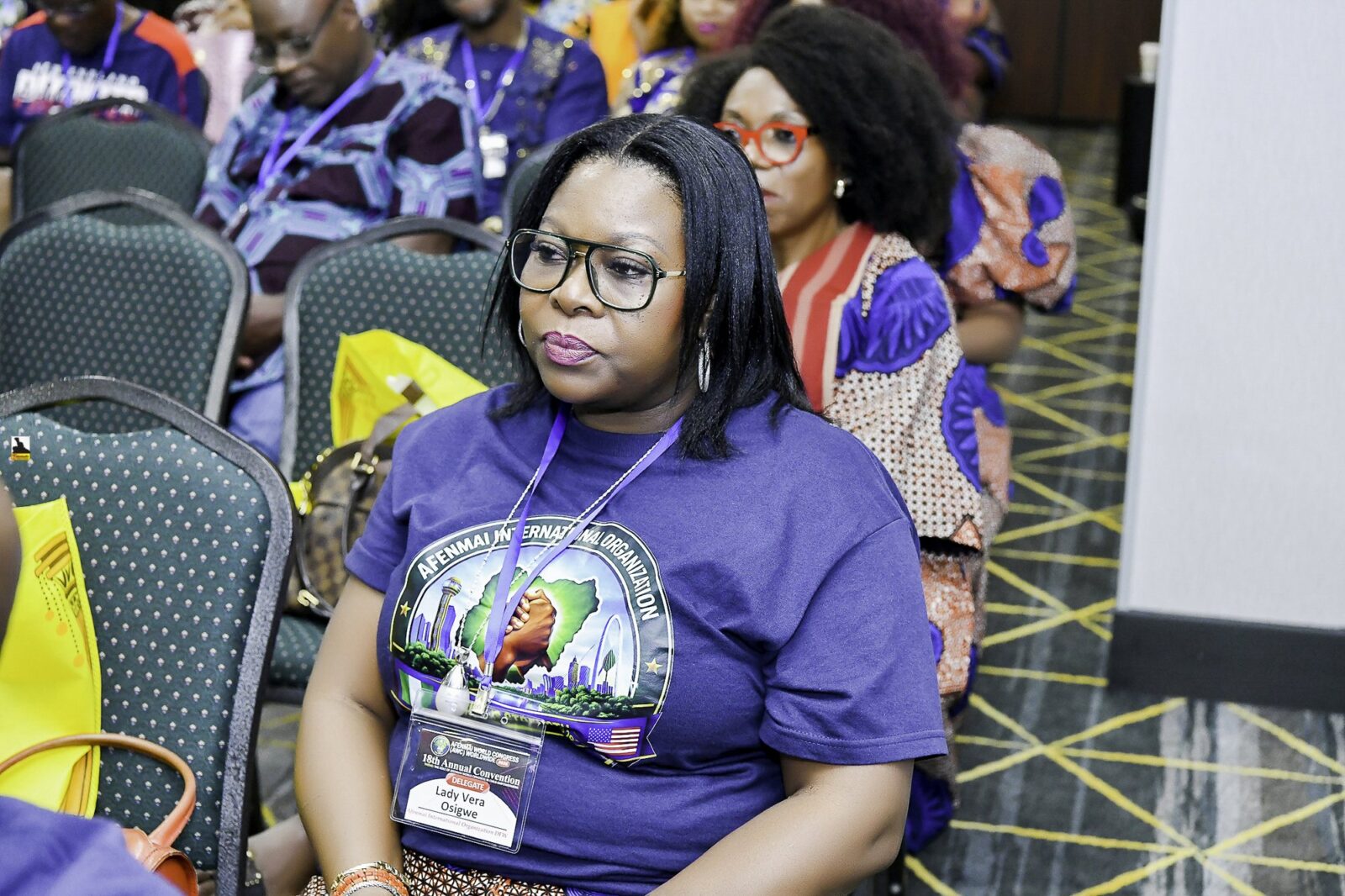 Woman in a convention T-shirt seated in the room