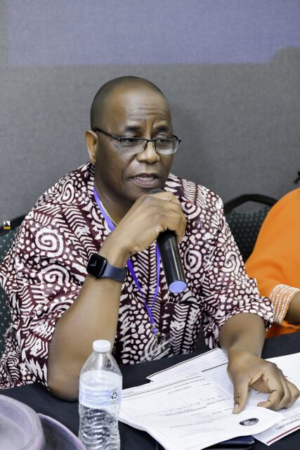 Man in a patterned shirt resting his chin on his hand