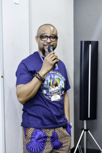 Man in a convention T-shirt holding a microphone