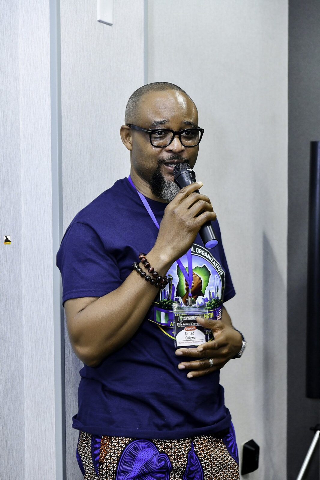 Man in a convention T-shirt holding a microphone