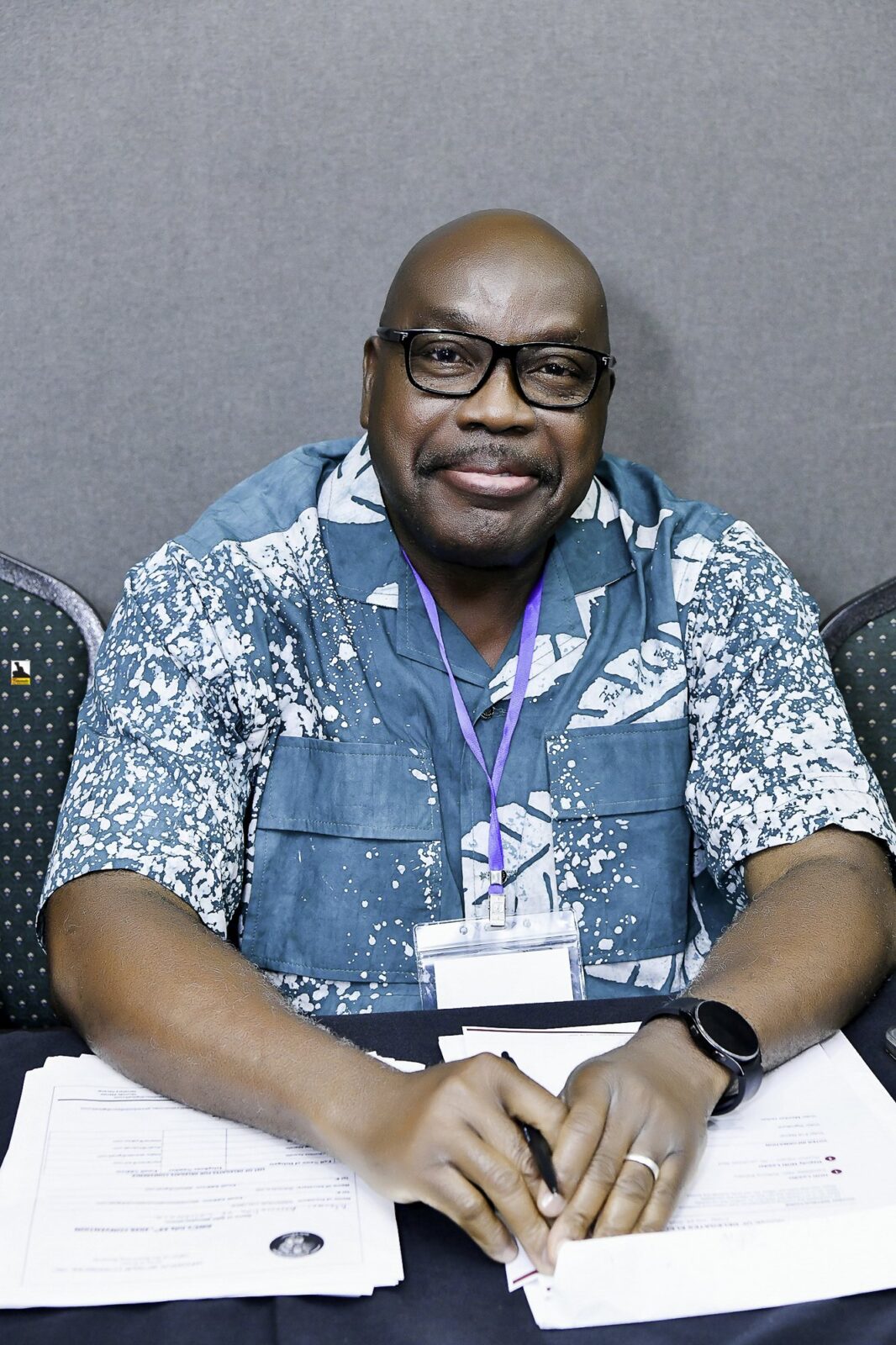 Smiling man in a blue patterned shirt at a table