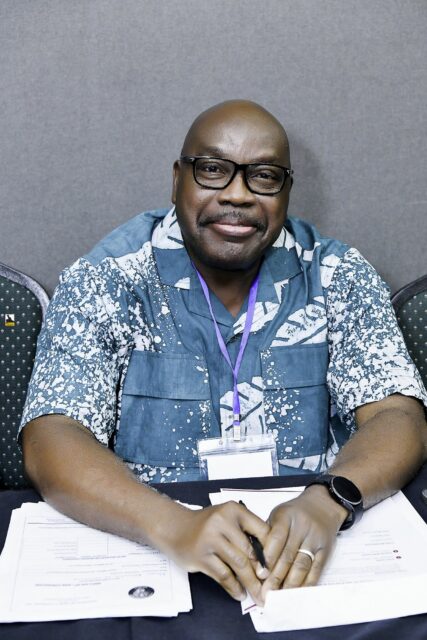 Smiling man in a blue patterned shirt at a table