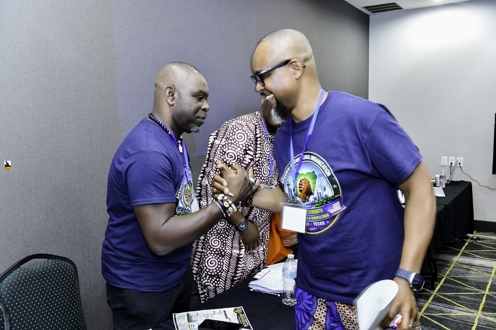 Two men in convention T-shirts sharing a microphone conversation
