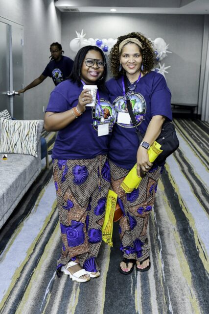 Two women in convention T-shirts and patterned skirts standing together