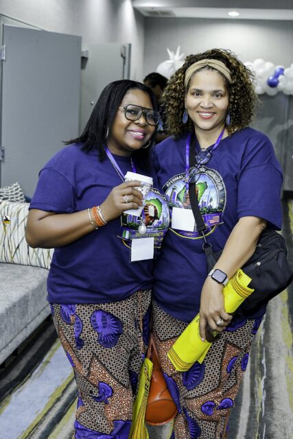 Two women in convention T-shirts and patterned skirts standing together