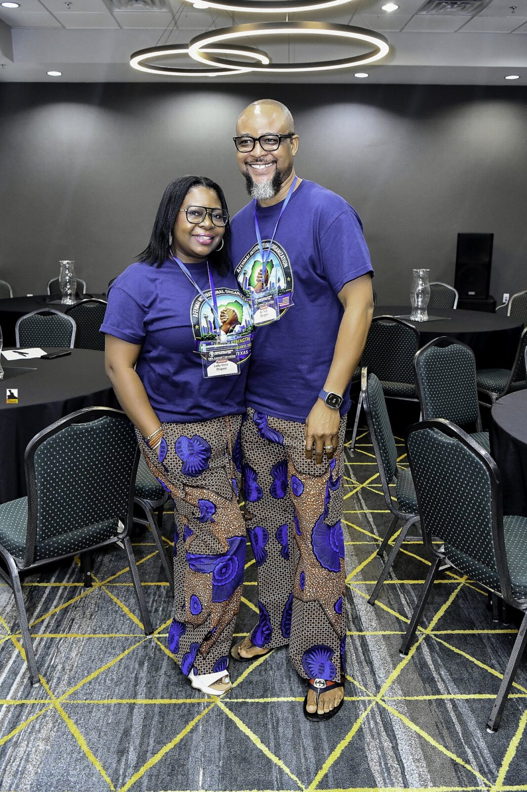Woman in patterned clothing and man in a convention T-shirt posing together