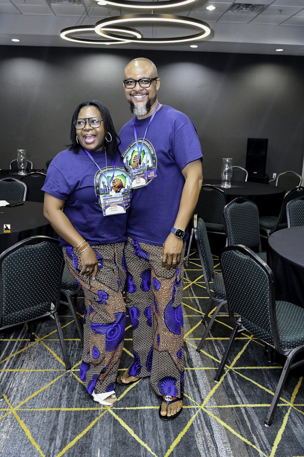 Woman in patterned clothing and man in a convention T-shirt posing together