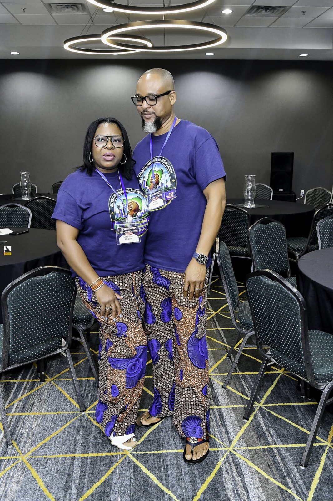 Woman in patterned clothing and man in a convention T-shirt posing together