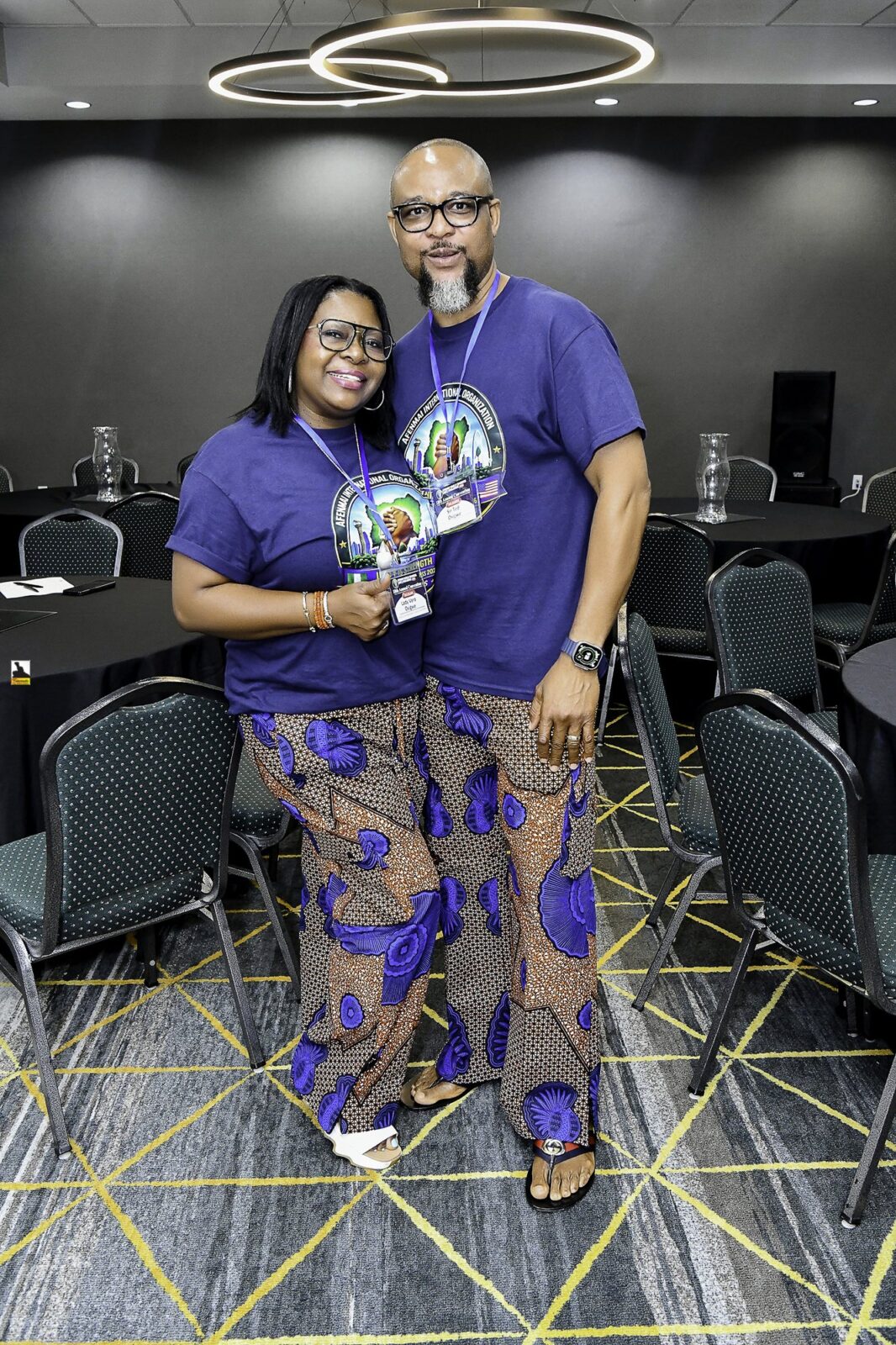 Woman in patterned clothing and man in a convention T-shirt posing together