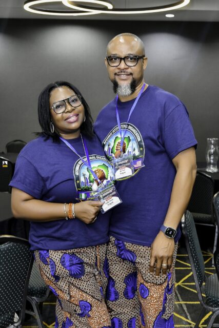 Woman in patterned clothing and man in a convention T-shirt posing together