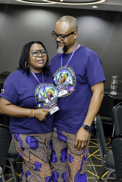 Woman in patterned clothing and man in a convention T-shirt posing together