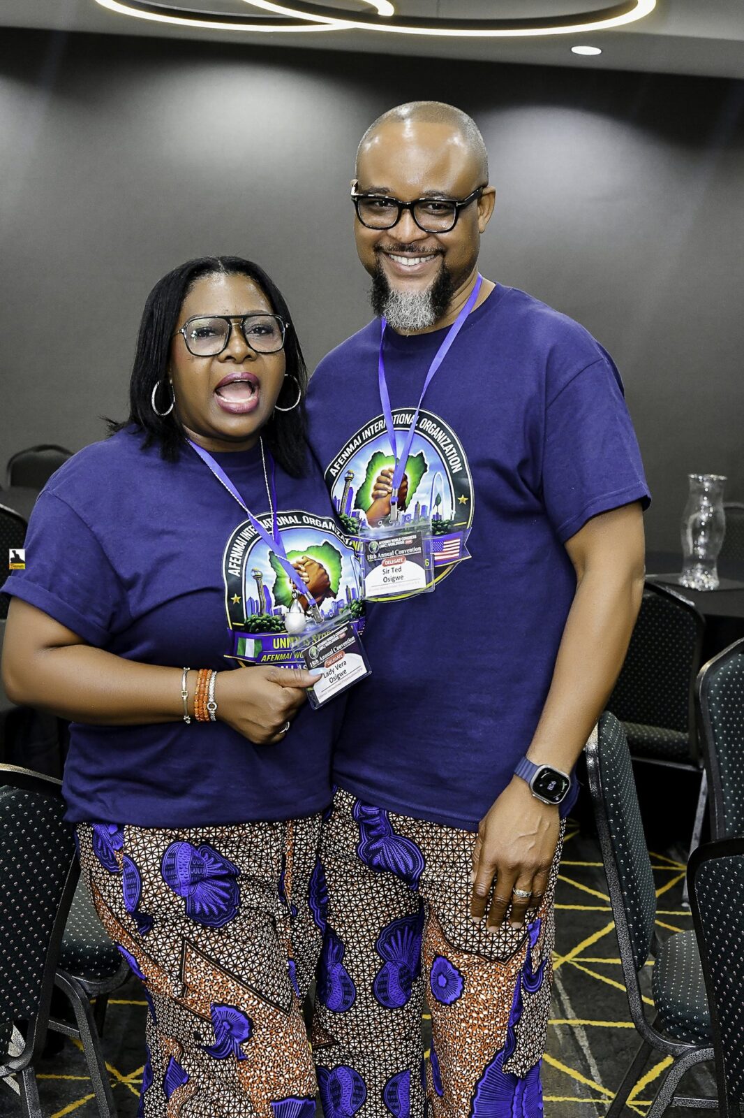 Woman in patterned clothing and man in a convention T-shirt posing together