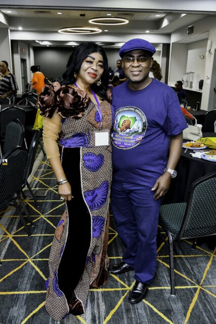 Woman in patterned blue clothing beside a man wearing a cap