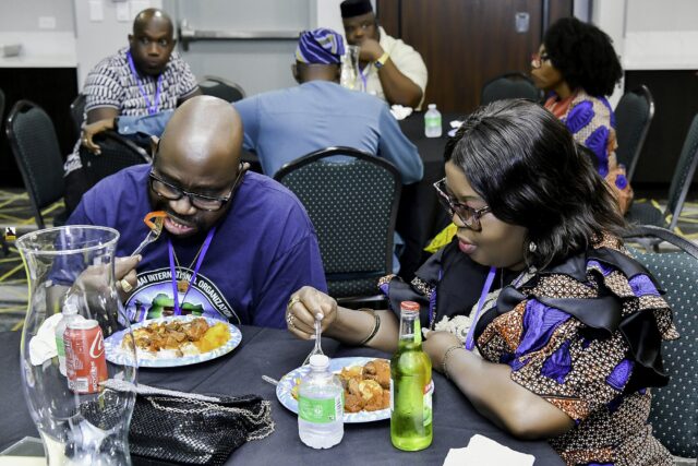 Convention attendees eating and talking around a table
