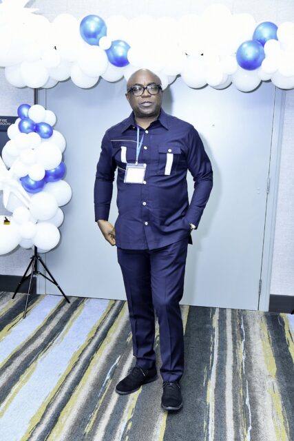 Man in a blue convention T-shirt posing by balloons