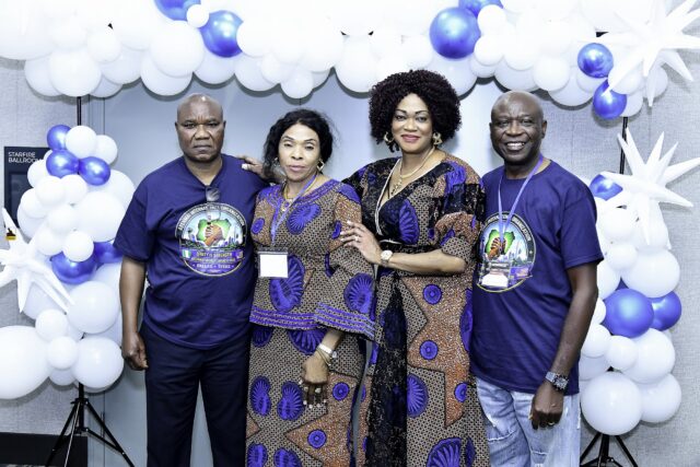Four attendees in blue shirts and patterned clothing posing together
