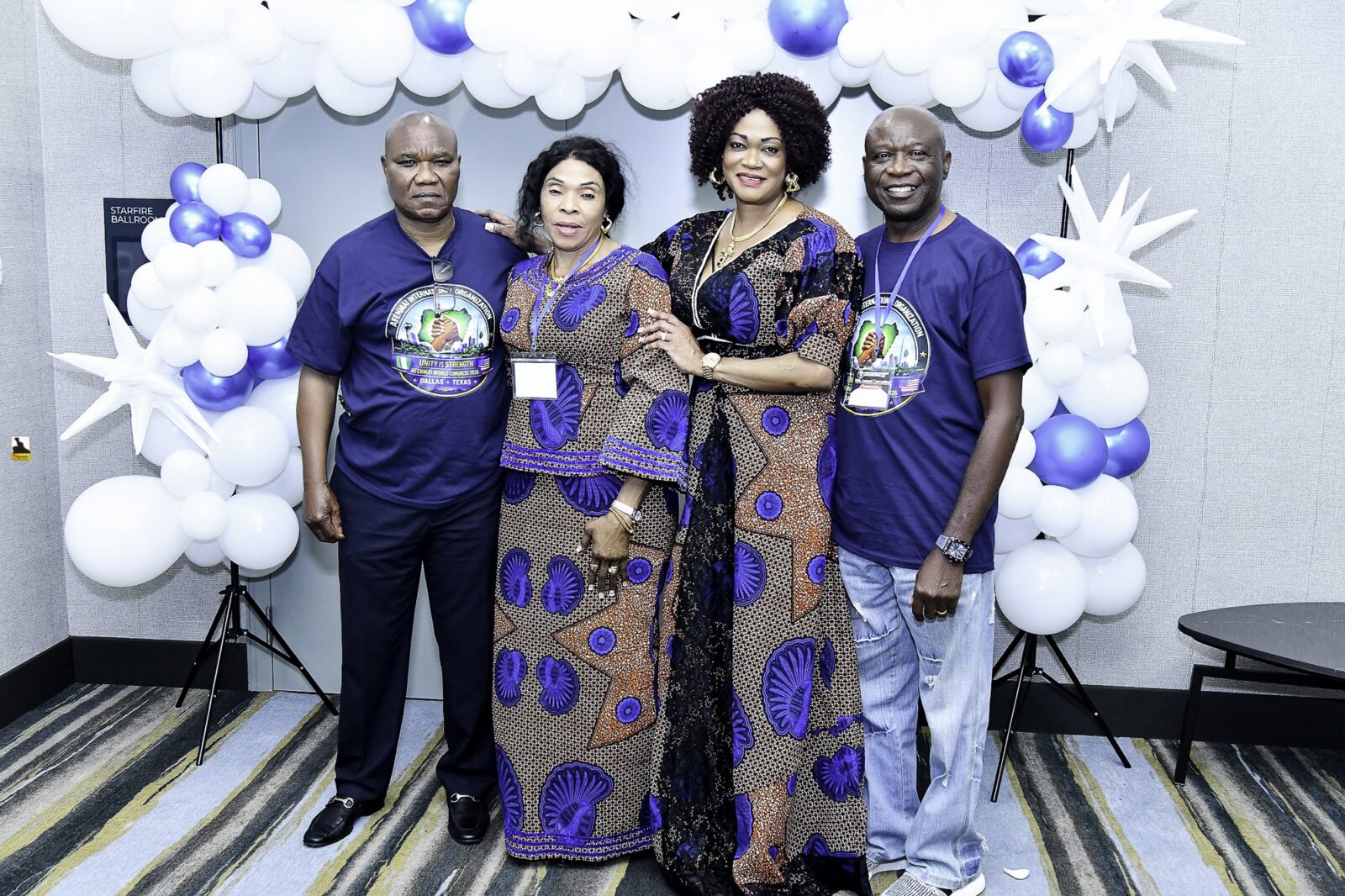 Four attendees in blue shirts and patterned clothing posing together