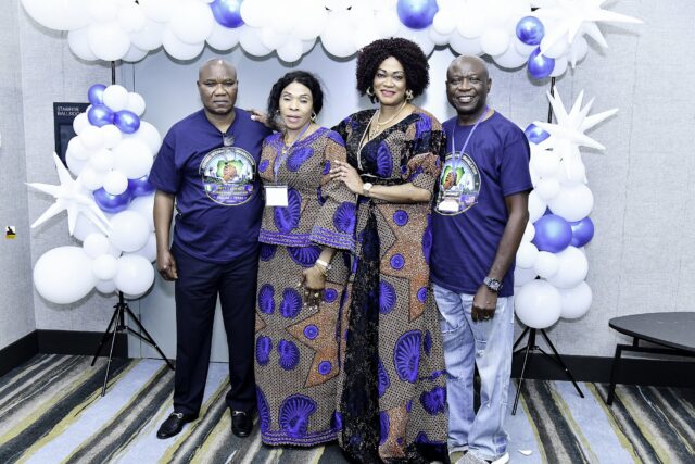 Four attendees in blue shirts and patterned clothing posing together