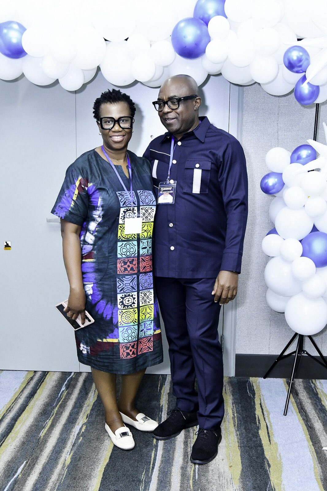 Man in a suit and woman in a colorful patterned outfit standing together