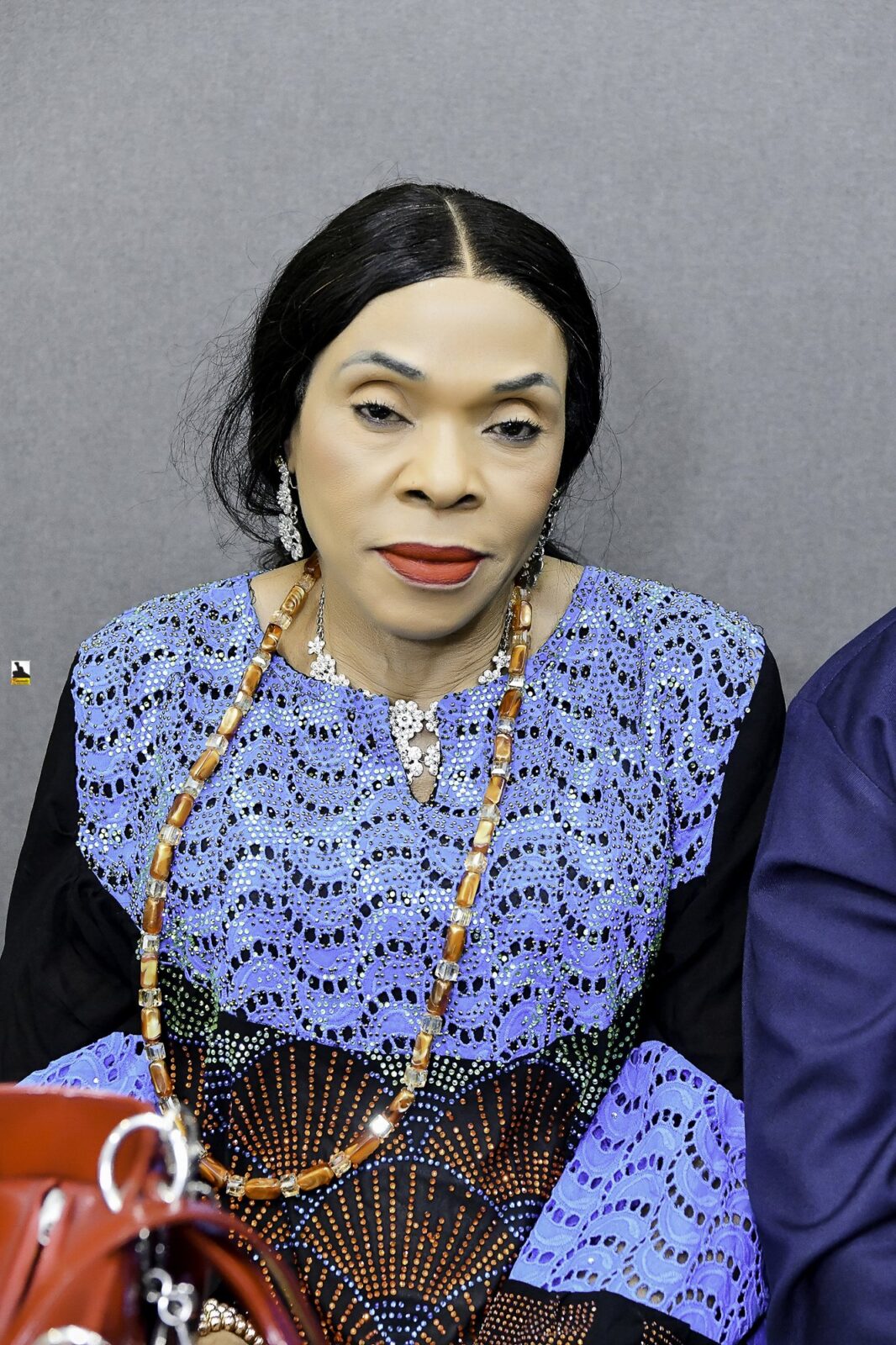 Woman in a blue patterned outfit seated in the room