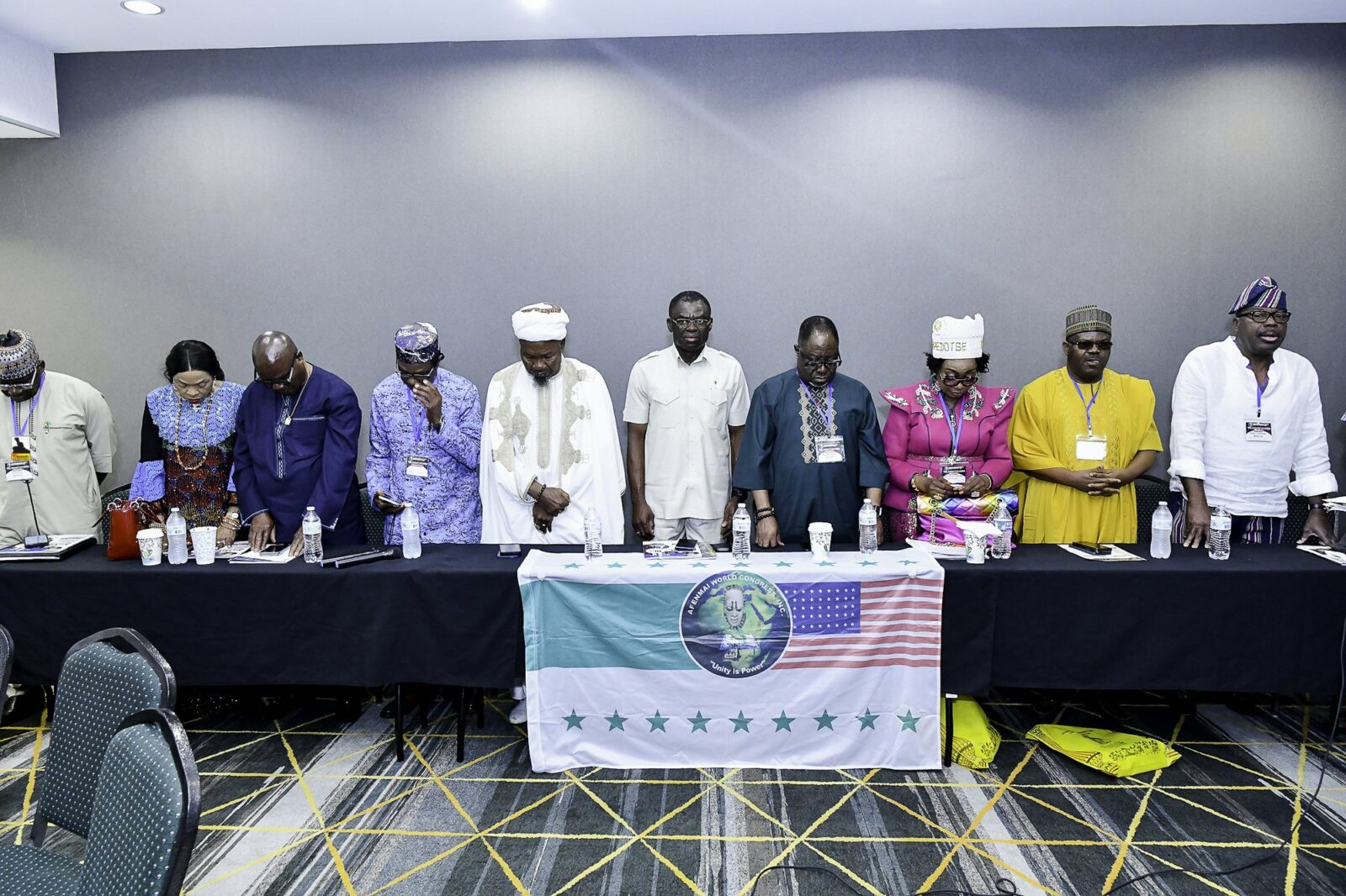 Attendees standing behind the front table with heads lowered