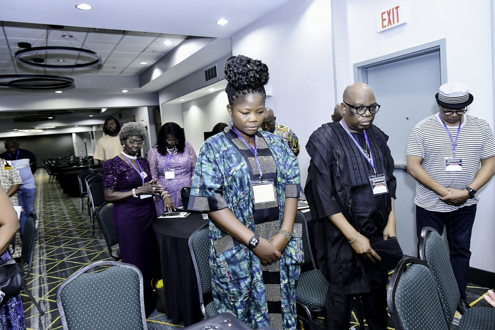Attendees standing beside their chairs with heads lowered