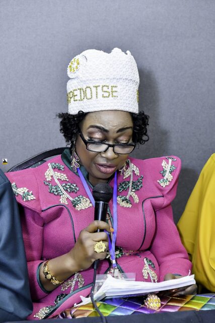 Woman in a floral jacket and white hat looking at notes