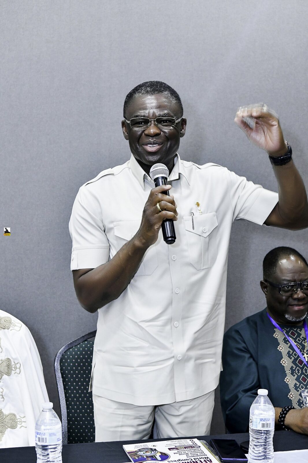 Man in a white shirt speaking into a microphone at the front table