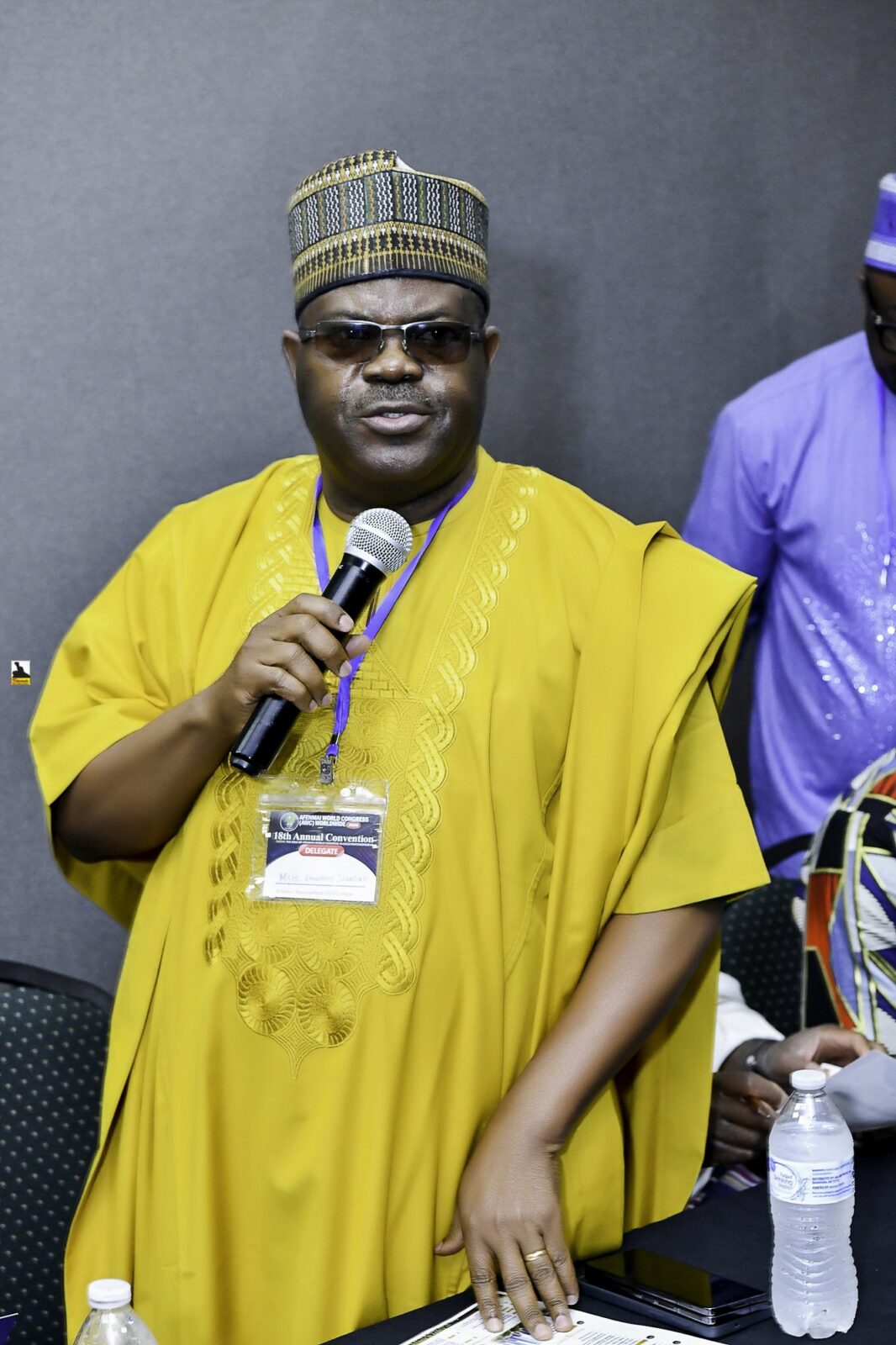 Man in yellow clothing holding a microphone