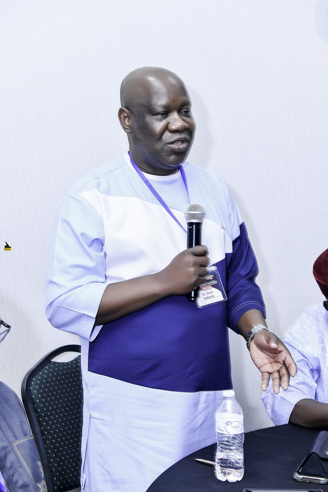 Man in white and blue clothing speaking into a microphone