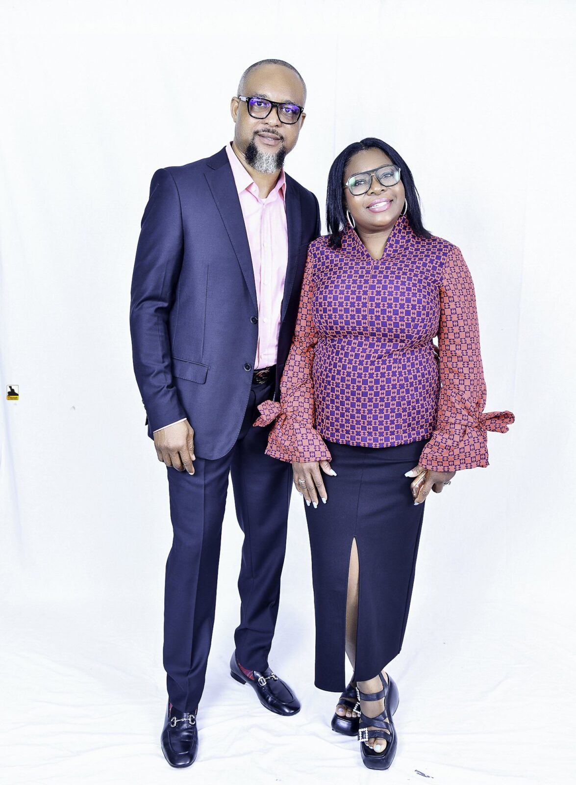 Man in a navy suit and woman in a patterned blouse posing together