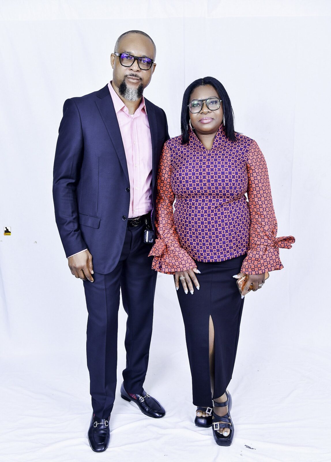 Man in a navy suit and woman in a patterned blouse posing together