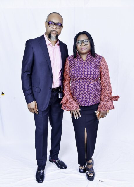 Man in a navy suit and woman in a patterned blouse posing together
