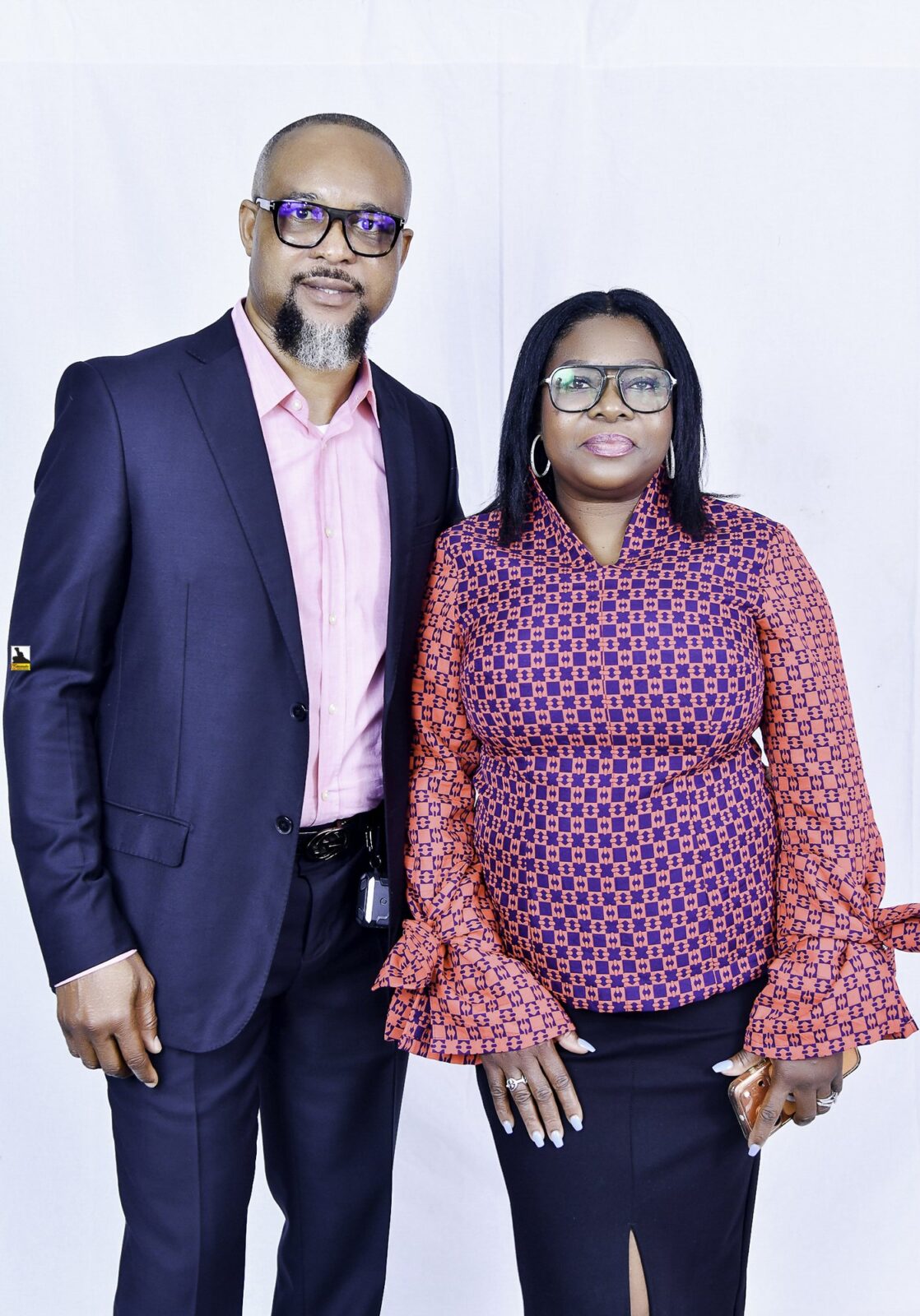 Man in a navy suit and woman in a patterned blouse posing together