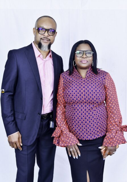 Man in a navy suit and woman in a patterned blouse posing together