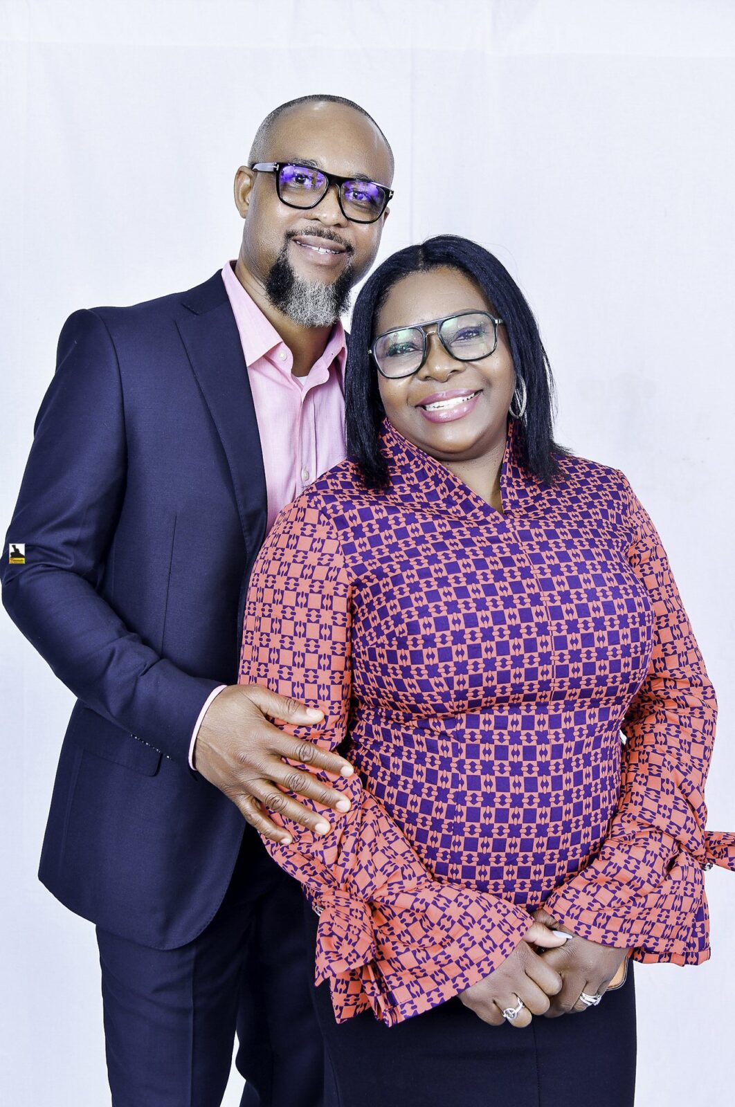 Man in a navy suit and woman in a patterned blouse posing together
