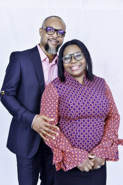 Man in a navy suit and woman in a patterned blouse posing together