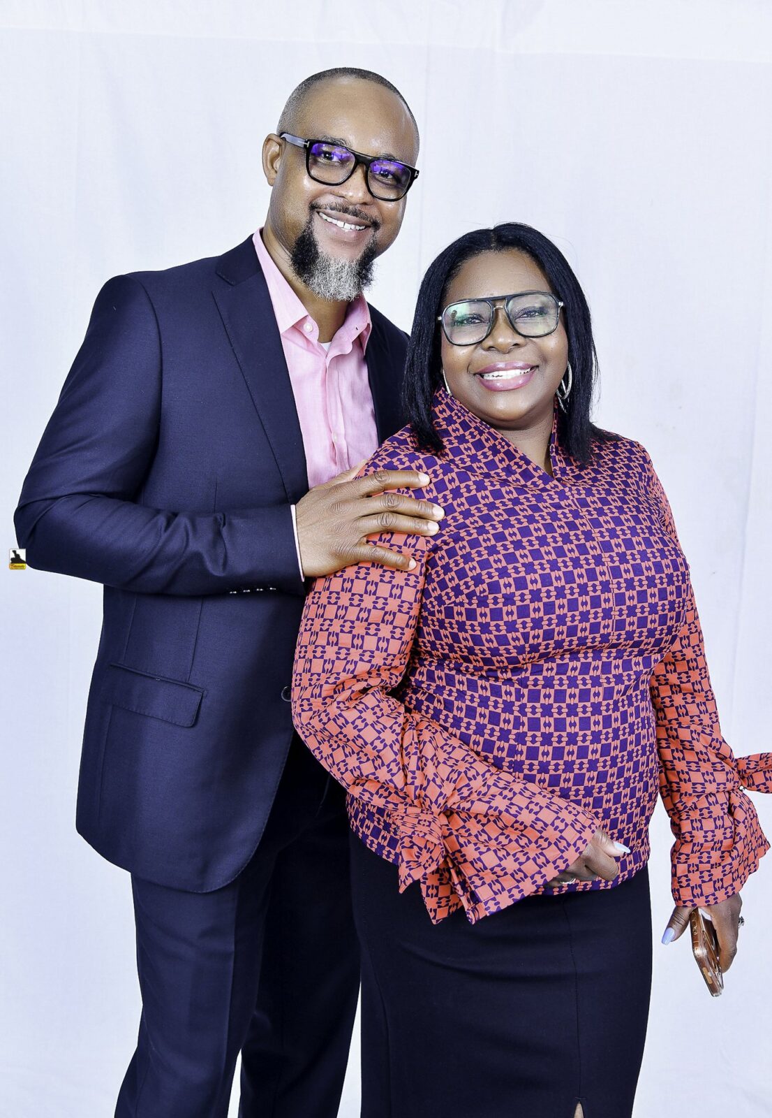 Man in a navy suit and woman in a patterned blouse posing together