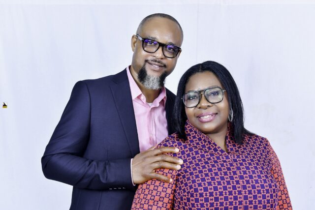 Man in a navy suit and woman in a patterned blouse posing together