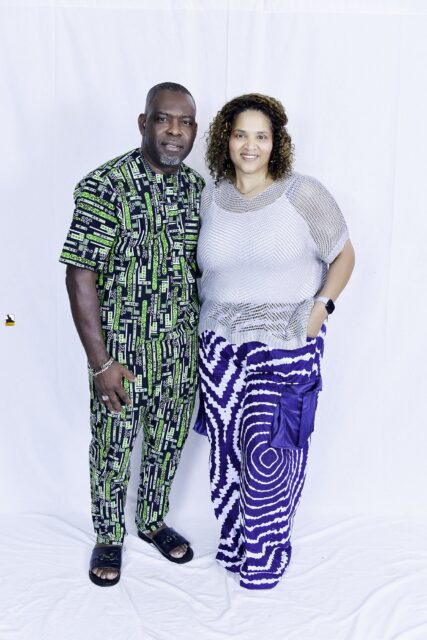 Man in green patterned clothing and woman in a light top posing together