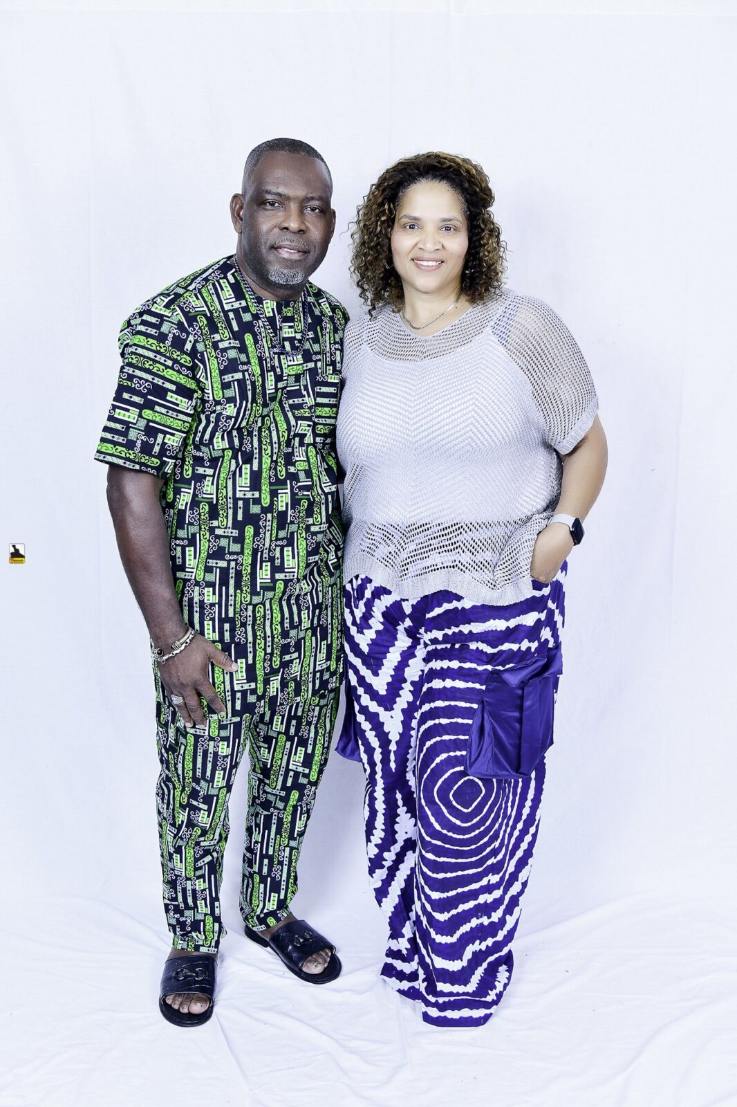 Man in green patterned clothing and woman in a light top posing together